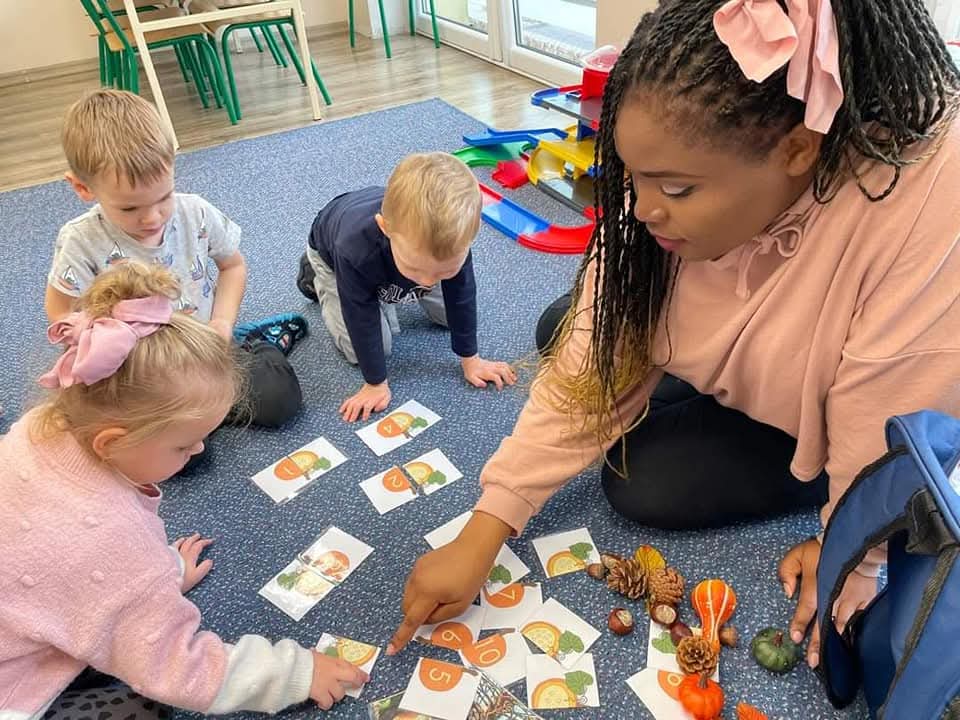 Teacher conducting an interactive English activity with young children using picture cards.